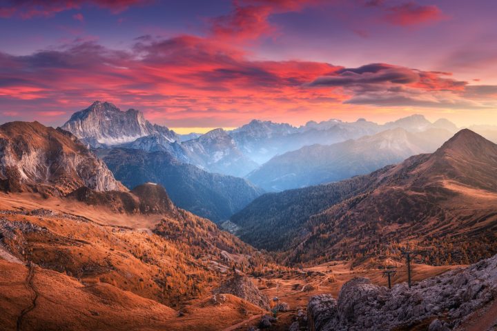 Colorful red sky with clouds over the beautiful mountains in fog