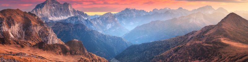 Colorful red sky with clouds over the beautiful mountains in fog