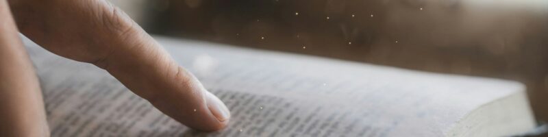 A young man is reading the holy scriptures pointing to a Bible topic. bible book Bible reading