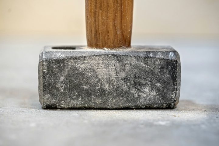 Closeup shot of a sledgehammer with shallow depth of field on a concrete floor