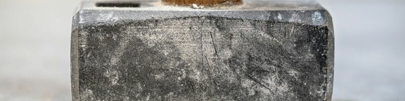 Closeup shot of a sledgehammer with shallow depth of field on a concrete floor