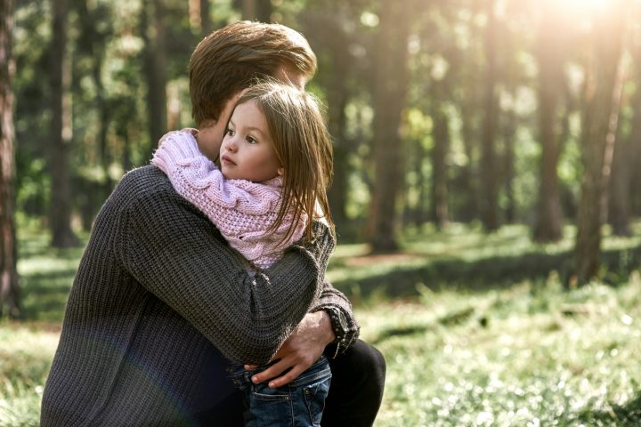 Little girl huggs her father in forest
