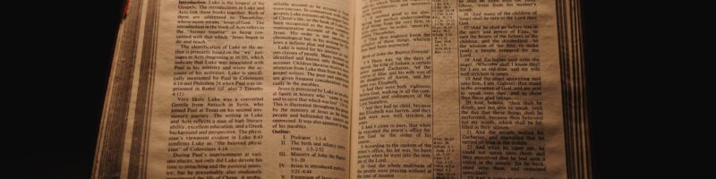 Closeup shot of a historic old Bible open on the St. Luke pages on display in a dark room