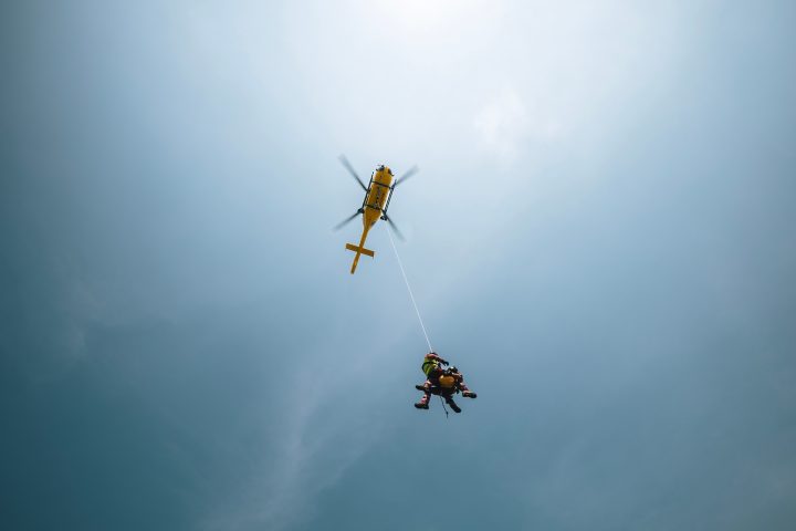 Paramedics hanging on rope under rescue helicopter