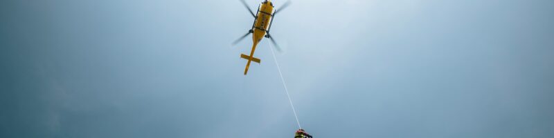 Paramedics hanging on rope under rescue helicopter