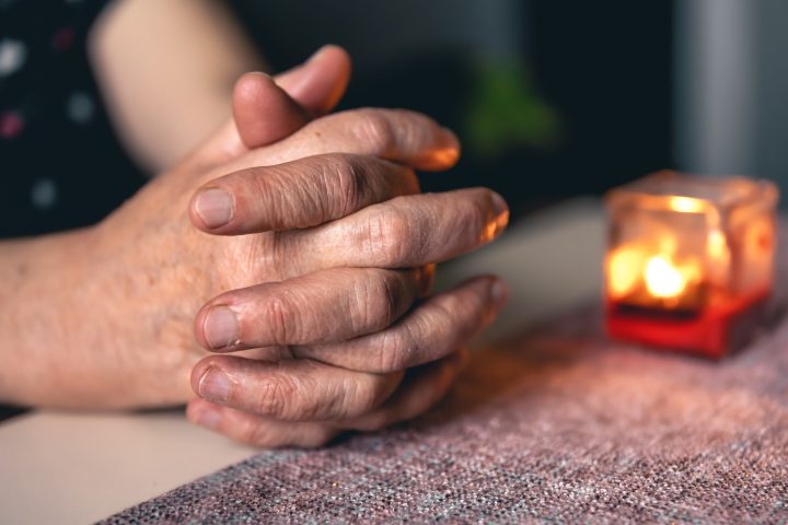 Hands of an old woman folded for prayer.